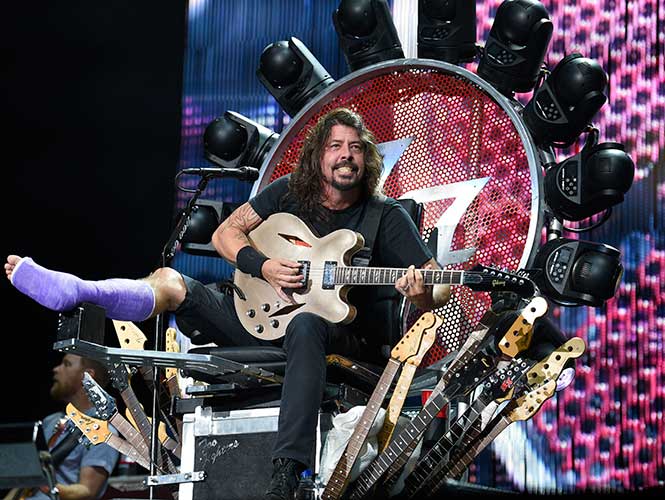 El ex integrante de Nirvana reapareció con su extremidad cubierta por un yeso púrpura y sentado, cual monarca, en un trono pletórico enmarcado por luces y mástiles de guitarras. (AP)